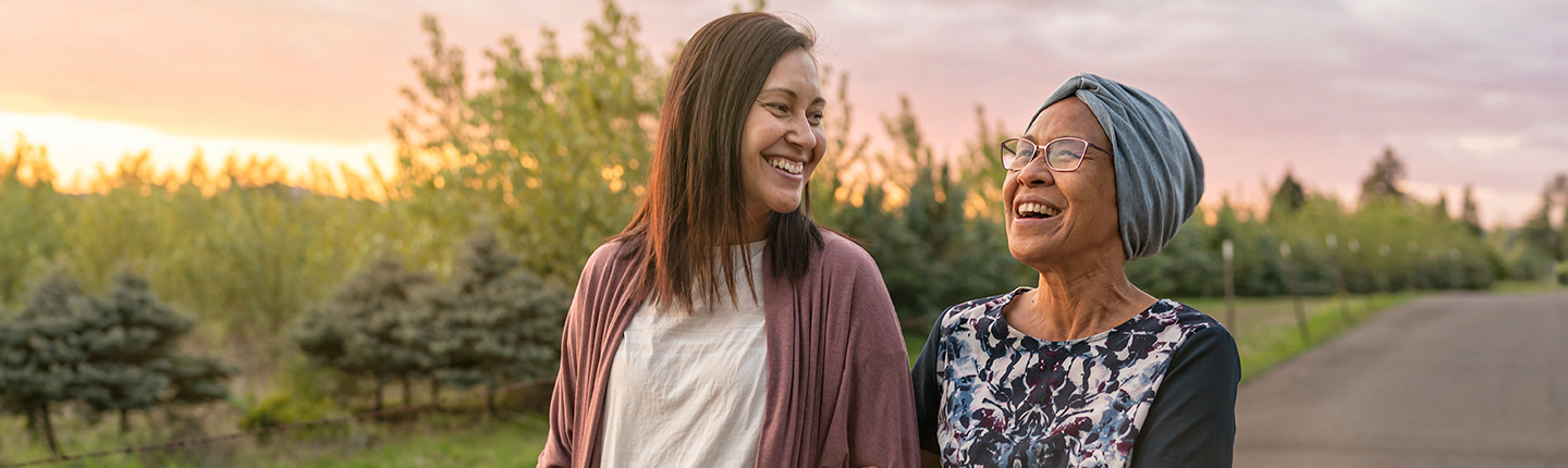 A joyous woman guides an older woman down a road